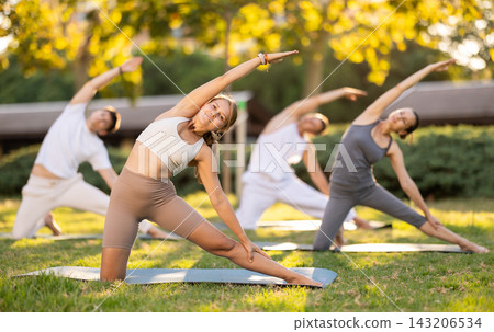 Girl leading outdoor group yoga class in summer park Girl leading outdoor group yoga class in summer park 143206534