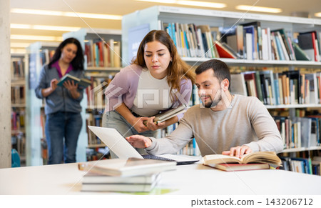 Male and female students preparing for exam together in library Male and female students preparing for exam together in library 143206712