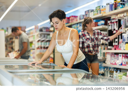 Woman purchasing frozen food in grocery store Woman purchasing frozen food in grocery store 143206956
