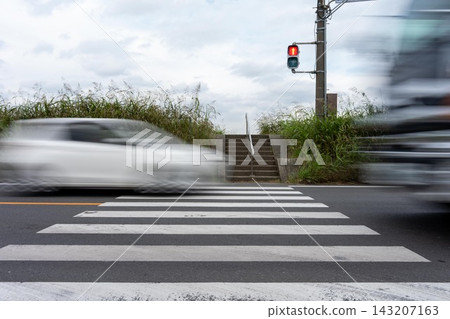 A car speeds through a pedestrian crossing against a red light. A car speeds through a pedestrian crossing against a red light. 143207163