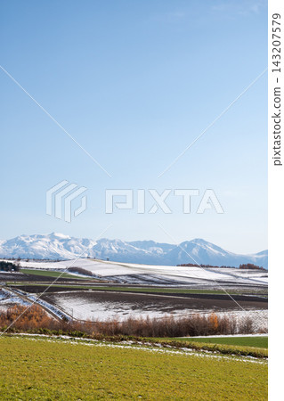 Snow-covered fields and snow-capped mountain ranges on a clear late autumn day: the Tokachi Mountain Range Snow-covered fields and snow-capped mountain ranges on a clear late autumn day: the Tokachi Mountain Range 143207579