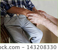 An elderly woman's hands holding both hands of an elderly man. 143208330