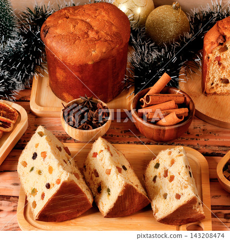 Sliced classic panettone in a Christmas setting, highlighting the soft dough, candied fruit pieces, and raisins on a decorated table. Sliced classic panettone in a Christmas setting, highlighting the soft dough, candied fruit pieces, and raisins on a decorated table. 143208474