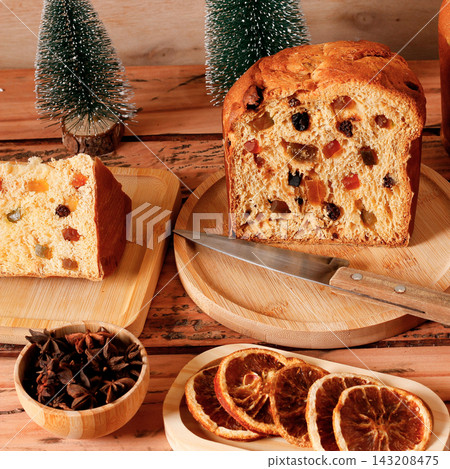 Traditional panettone with visible candied fruit and raisins, sliced on a table in a Christmas setting. Traditional panettone with visible candied fruit and raisins, sliced on a table in a Christmas setting. 143208475