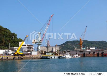 藍天下，港口裡起重機正在卸貨的畫面。 143209053