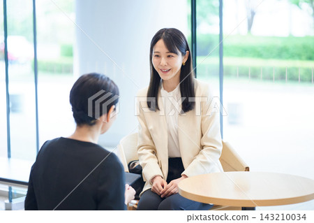 一位面帶微笑的女士在休息室遞給顧客一張名片。 143210034
