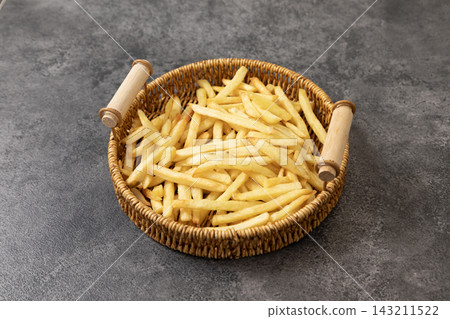 Golden crispy french fries served in a woven wicker basket on a dark gray stone background Golden crispy french fries served in a woven wicker basket on a dark gray stone background 143211522
