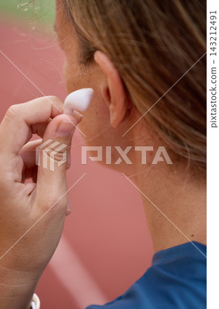 Close-up of woman putting wireless earbud in ear before running Close-up of woman putting wireless earbud in ear before running 143212491
