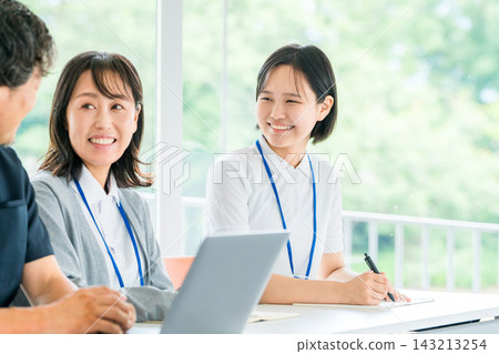 A young female nurse interacts with senior staff members with a smile. This illustrates new employee training and workplace communication at the hospital. A young female nurse interacts with senior staff members with a smile. This illustrates new employee training and workplace communication at the hospital. 143213254