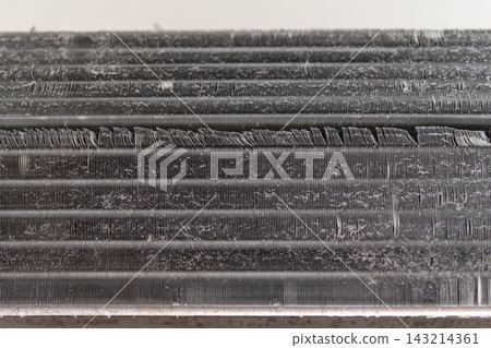 Dust lint have accumulated across the metal fins of an air conditioner cooling coil showing the need for cleaning maintenance Dust lint have accumulated across the metal fins of an air conditioner cooling coil showing the need for cleaning maintenance 143214361