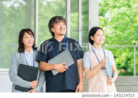 A doctor and a female caregiver smile at the entrance of the facility. The teamwork of these three people supporting medical care and nursing care. A doctor and a female caregiver smile at the entrance of the facility. The teamwork of these three people supporting medical care and nursing care. 143214723
