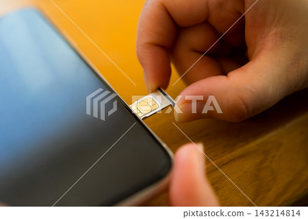 The hand that pulls out the SIM card tray of the smartphone The hand that pulls out the SIM card tray of the smartphone 143214814