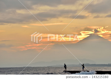 日落時分,人們在久沼海灘的海堤上釣魚的剪影。 日落時分,人們在久沼海灘的海堤上釣魚的剪影。 143215160
