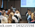 Conference audience seated along a central aisle 143215598