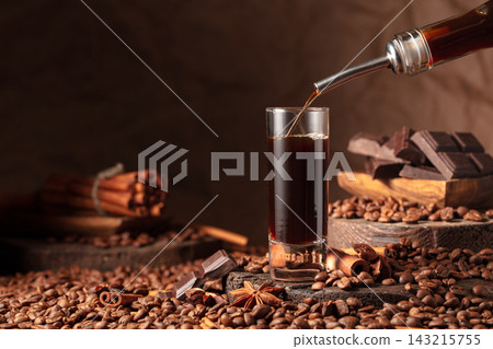 Coffee liquor is poured from a bottle into a glass. Coffee liquor is poured from a bottle into a glass. 143215755