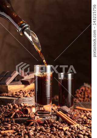 Coffee liquor is poured from a bottle into a glass. 143215756