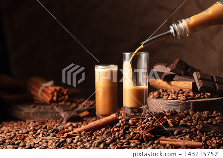 Irish cream and coffee liquor is poured from a bottle into a glass. Irish cream and coffee liquor is poured from a bottle into a glass. 143215757