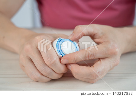 A woman is applying a continuous glucose monitoring sensor to her arm. A woman is applying a continuous glucose monitoring sensor to her arm. 143217852