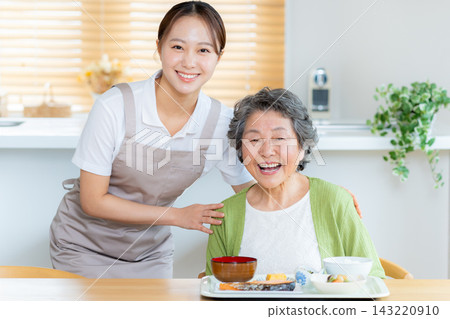 一位護理員和一位老婦人正在準備餐點。 一位護理員和一位老婦人正在準備餐點。 143220910