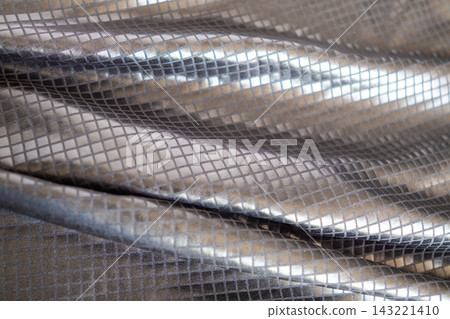 Folded metallic silver fabric with square grid texture and reflective shimmer for design Folded metallic silver fabric with square grid texture and reflective shimmer for design 143221410
