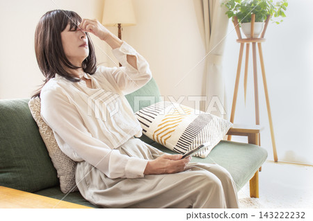 一位中年婦女,因過度使用智慧型手機而眼睛疲勞。 一位中年婦女,因過度使用智慧型手機而眼睛疲勞。 143222232