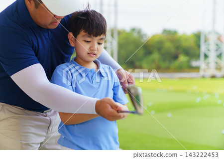 Golf instructor helping young Asian boy adjust swing posture at driving range Golf instructor helping young Asian boy adjust swing posture at driving range 143222453
