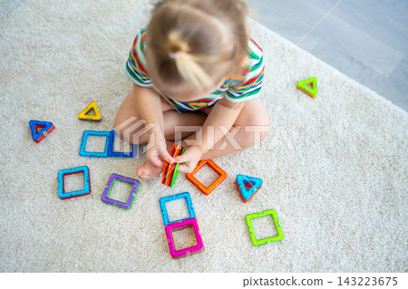 Little girl playing colorful magnet plastic blocks kit at home. The child playing educational games. Early childhood development. Little girl playing colorful magnet plastic blocks kit at home. The child playing educational games. Early childhood development. 143223675