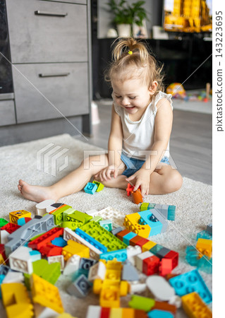 Caucasian child a little girl is playing in the constructor at home. Educational toys for children. Caucasian child a little girl is playing in the constructor at home. Educational toys for children. 143223695