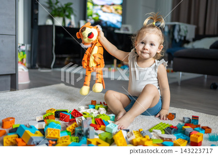 Caucasian child a little girl is playing in the constructor at home. Educational toys for children. Caucasian child a little girl is playing in the constructor at home. Educational toys for children. 143223717