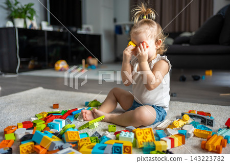 Caucasian child a little girl is playing in the constructor at home. Educational toys for children. Caucasian child a little girl is playing in the constructor at home. Educational toys for children. 143223782