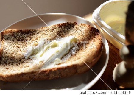 The shadow of the blinds cast on whole wheat bread and margarine, and the rising sun. 143224366
