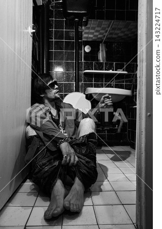 Drunk Man Sitting on Bathroom Floor with Alcohol Bottle Drunk Man Sitting on Bathroom Floor with Alcohol Bottle 143224717