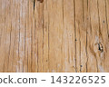 Aged wood surface showing natural texture with vertical grain lines, cracks, and knots, forming an abstract rustic background and timber pattern 143226525