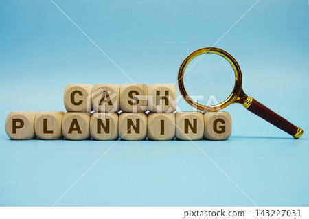 Cash Planning alphabet letters wooden cube and magnifying glass on blue background Cash Planning alphabet letters wooden cube and magnifying glass on blue background 143227031