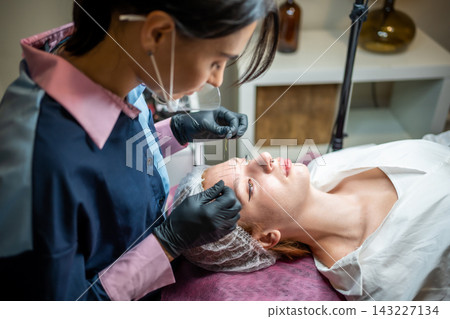 Permanent makeup cosmetologist master takes measurements for the new shape of the eyebrows of model. Microblading preparation Permanent makeup cosmetologist master takes measurements for the new shape of the eyebrows of model. Microblading preparation 143227134