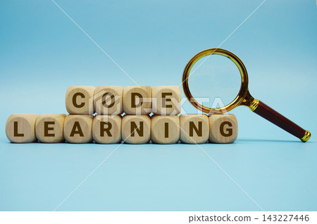 Code Learning alphabet letters wooden cube and magnifying glass on blue background Code Learning alphabet letters wooden cube and magnifying glass on blue background 143227446