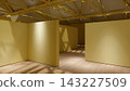 3D render of an empty exhibition gallery with yellow walls, wooden floors, exposed ceiling trusses, and track lighting. 143227509