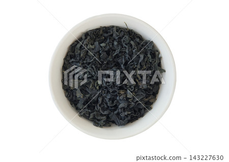 Undaria pinnatifida. Dried seaweed in a ceramic bowl isolated on a white background. Asian cuisine. Mineral rich. Gluten free. Top view. Undaria pinnatifida. Dried seaweed in a ceramic bowl isolated on a white background. Asian cuisine. Mineral rich. Gluten free. Top view. 143227630