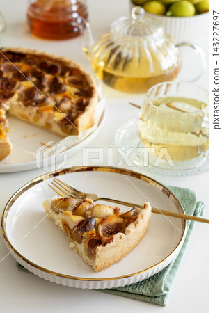 Slice of delicious fruit tart with figs and peaches served with herbal tea and honey Slice of delicious fruit tart with figs and peaches served with herbal tea and honey 143227697