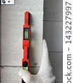 A close-up of a bubble level placed against a wall to measure the flatness of the surface. 143227997
