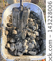 Heavy stones are into a metal cart. Manual labor, demolition, recycling construction materials, and DIY building projects. 143228006