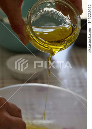 Golden Olive Oil Pouring Into White Bowl Golden Olive Oil Pouring Into White Bowl 143228052