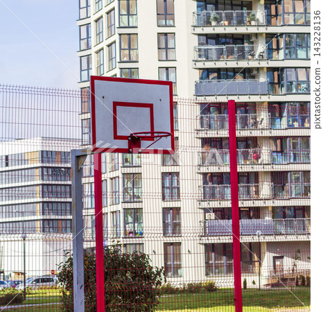 Outdoor sports court with a red mesh fence in front of modern apartments Outdoor sports court with a red mesh fence in front of modern apartments 143228136