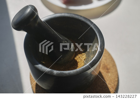 Ground spices in black mortar with pestle beside raw meat Ground spices in black mortar with pestle beside raw meat 143228227
