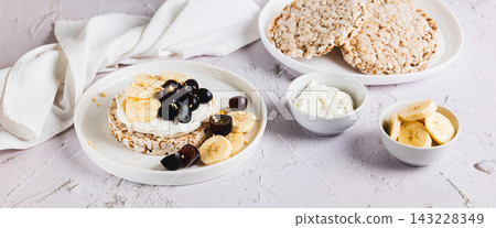 Rice bread with ricotta, banana, and grapes on a plate on the table web banner Rice bread with ricotta, banana, and grapes on a plate on the table web banner 143228349