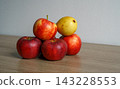 Red apples and a yellow pear are arranged on a wooden table. Concept of fruit, harvest, food, nutrition, abundance, freshness and still life setting 143228553