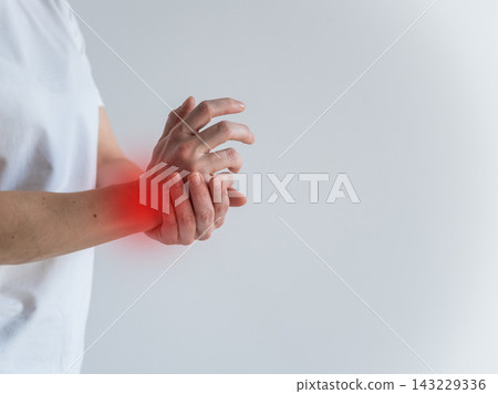 A woman suffers from wrist pain. The source of the pain is depicted as a red spot. A woman suffers from wrist pain. The source of the pain is depicted as a red spot. 143229336