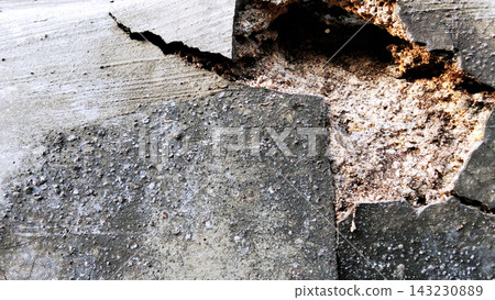 A severely damaged concrete wall with a large hole and exposed layers of plaster. A severely damaged concrete wall with a large hole and exposed layers of plaster. 143230889