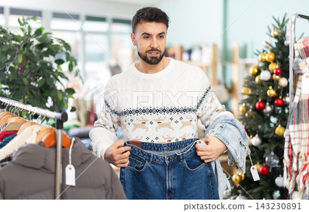 Young man choosing jeans in clothing store Young man choosing jeans in clothing store 143230891