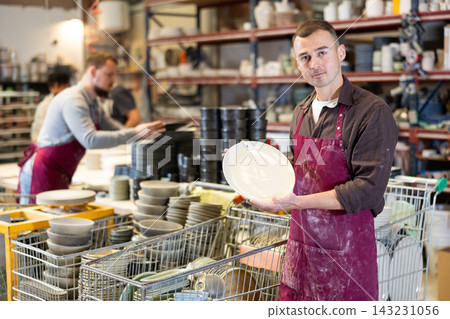Enthusiastic ceramicist demonstrating handcrafted plates in ceramic studio Enthusiastic ceramicist demonstrating handcrafted plates in ceramic studio 143231056